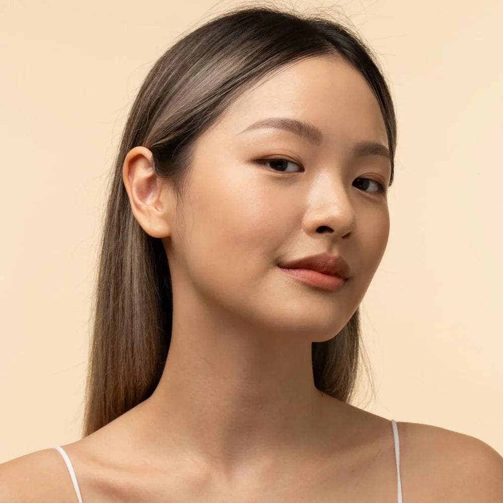 Woman with long hair and a neutral expression on a beige background